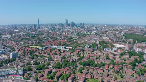 Dolly back drone shot of City of London skyscrapers from residential Southwark