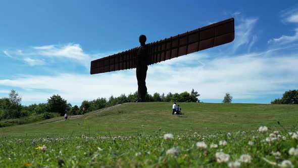 Angel of the North. Couple with pram walk along the front of the Angel Of The North in the North of