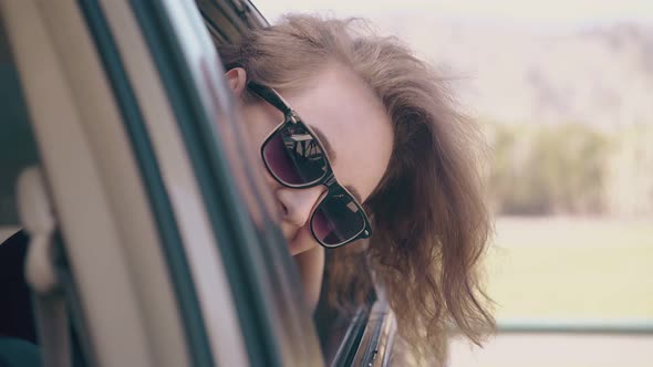 Joyful Girl Looks and Climbs Out Through Auto Window