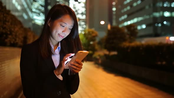 Business woman text on cellphone at night