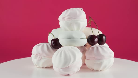 Coloured Marshmallows and Cherry at Plate Rotation Over Pink Background. 