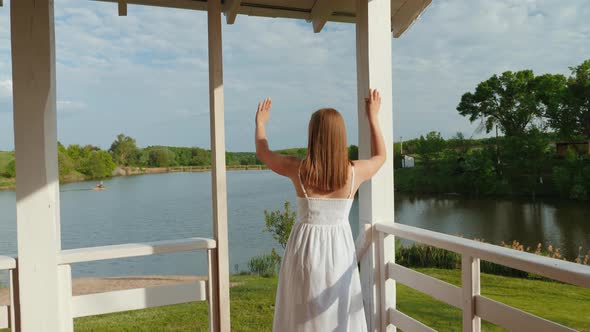 Young Woman Waves to Her Husband Who is Fishing on the Lake