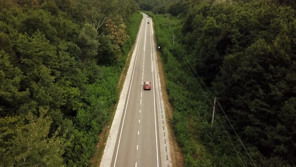 Orange SUV Car Driving on a Rural Road in the Mountains and Forest at Summer Sunny Day - Drone Point