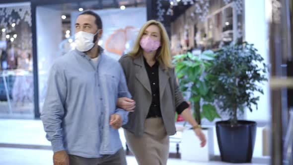 Confident Caucasian Couple in Covid-19 Face Masks Approaching To Shop Entrance in Mall and Entering