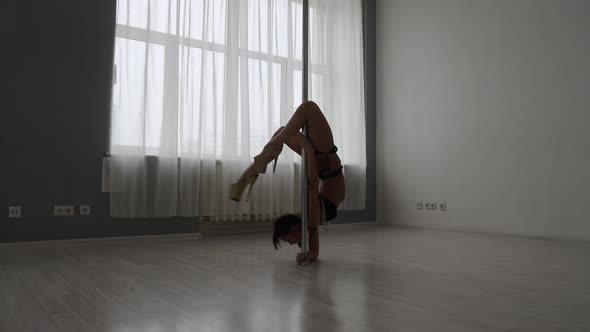 Flexible Woman Dancing on Pole in Studio