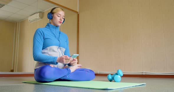 Young Woman in Headphones Meditates to Calm Music She Turns on Music Through an Online Application