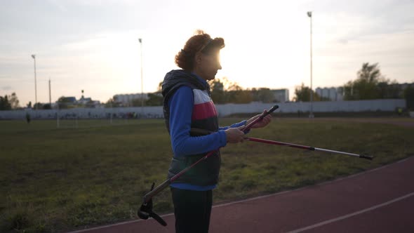Senior Woman Opens Nordic Walking Poles in the City's Stadium
