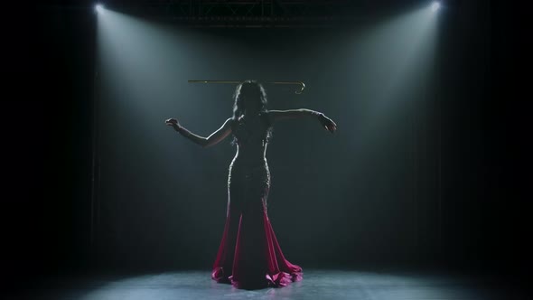 Arabian Belly Dancer in Exotic Dance Holding a Golden Cane on His Head. Silhouettes. Shot in a Dark