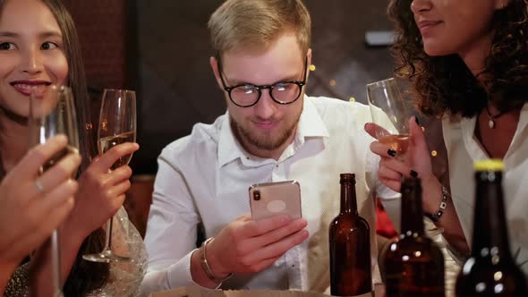 Friends in a Pub Celebrate and Have Fun, One Guy Is Looking at a Smartphone, and Not Talking