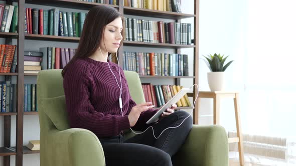 Casual Sitting Woman Listening Music on Tablet Computer