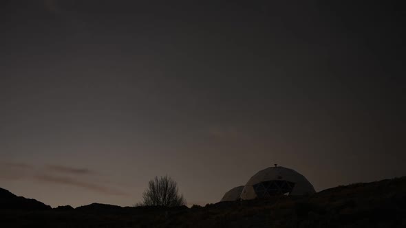 Time lapse of night falling over geodesic domes in wilderness