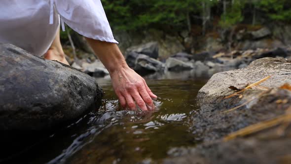 Hands Touching Flowing River Water