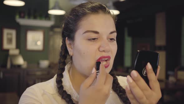 Portrait of Attractive Confident Plump Woman Painting Lips with Bright Red Lipstick