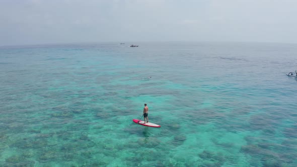 Young Man Floats on Red Surf on the Clear Azure Calm Waters of the Indian Ocean