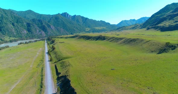 Aerial Rural Mountain Road and Meadow at Sunny Summer Morning. Asphalt Highway and River.