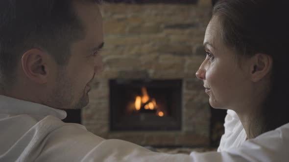 A couple in love is kissing by the fireplace, in which a fire is burning