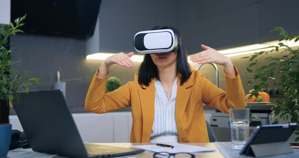 Businesswoman Sitting in Contemporary Kitchen Near the Table and Working in Virtual Reality