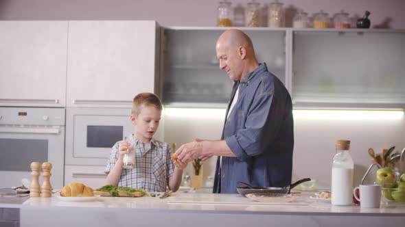 Father and Son Eating Bun in Kitchen in Morning