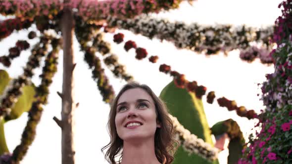 Girl Admires Hanging Flowers in a City Park