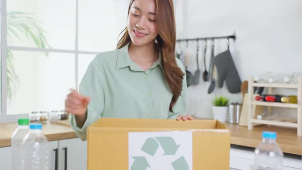 Portrait of Asian woman smile  hold trash bin for further recycling and look at camera at home.