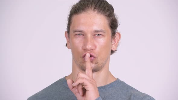 Happy Man with Finger on Lips Against White Background