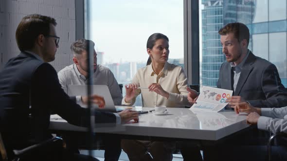 Corporate leader in suit telling team of colleagues financial statistics of company in office