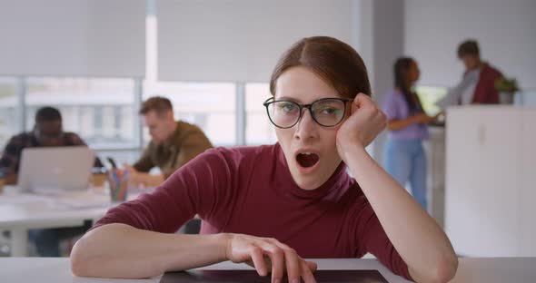 Depressed Young Woman Feeling Bored Sitting in Front of Laptop in Modern Office