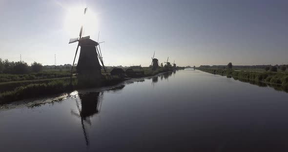 A drone shot panning forward, around Dutch Windmills during sunrise