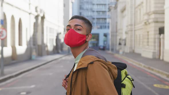 Mixed race man wearing face mask, turning around in the street