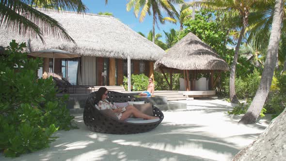 A man and woman couple relaxing and reading a book in the tropical islands in French Polynesia.