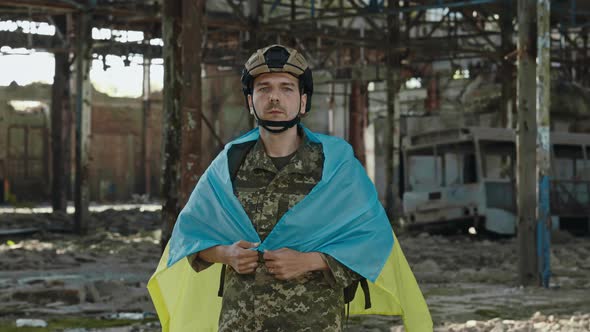 Soldier with Ukrainian Flag Standing on Destroyed Plant