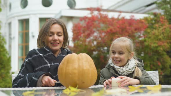 Mother Carves Pumpkin Jack-O-Lantern, Daughter Puts Candle Inside, Togetherness