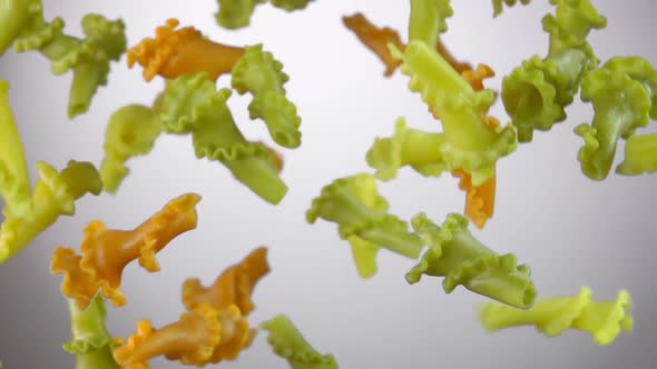 Colored Pasta Campanelle Is Flying Up and Falling Down on a White Background