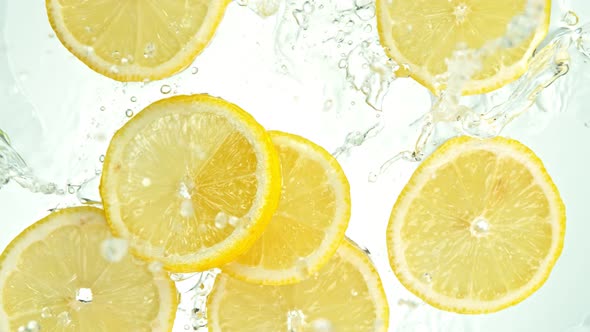 Super Slow Motion Shot of Lemon Slices Falling Into Water on White Background at 1000Fps.