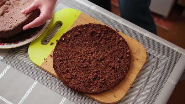 Woman Slicing Crust of Caramel Chocolate Cake on Wooden Cutting Board