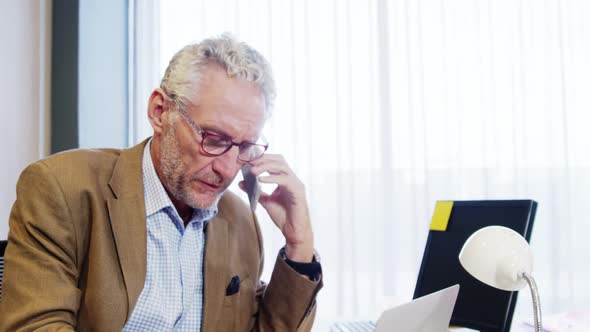 Businessman talking on mobile phone while working at desk