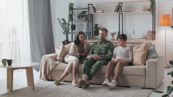 Army Officer Showing Photos to Family in Living Room