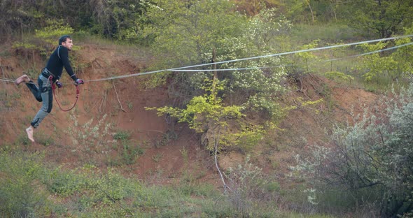 A Man Is Sitting Up on the Slackline Extreme Sports and Nature