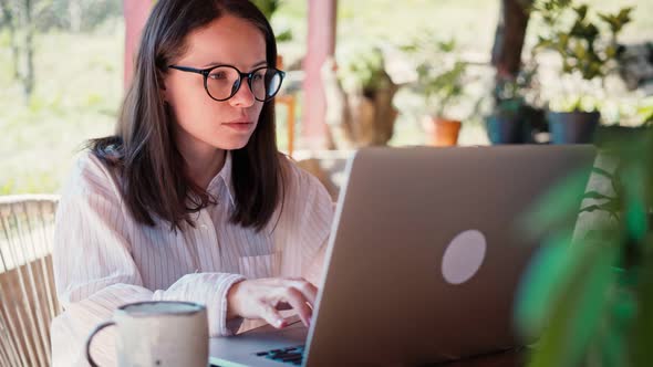 A Young Woman Freelancer Working on Her Laptop While Sitting on the Terrace