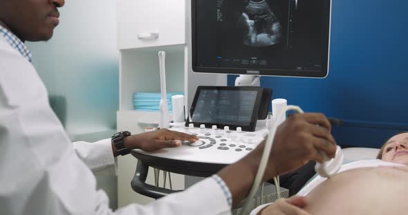 Close Up Cropped Shot of Hands of Male African Doctor Screening of Pregnant