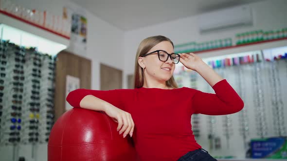 Lovely girl trying on new glasses at optics. 