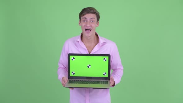 Happy Young Handsome Businessman Showing Laptop and Looking Surprised