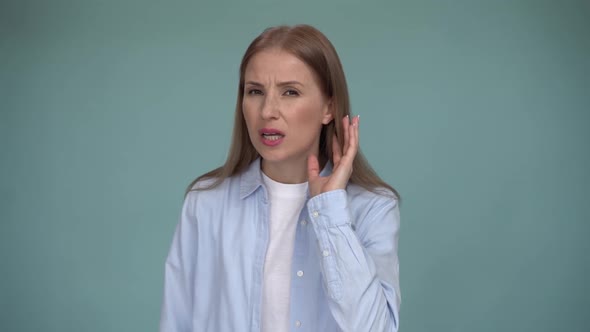 Portrait of attentive brunette woman holding hand near ear trying to listen quiet conversation
