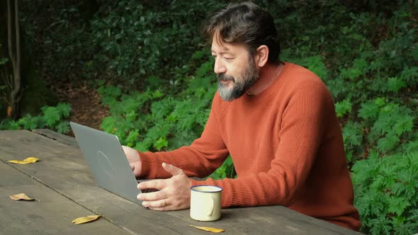 Side view of a man working with connection online and laptop computer in outdoors. Wireless