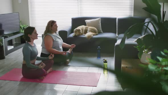 Caucasian lesbian couple keeping fit and meditating on yoga mat