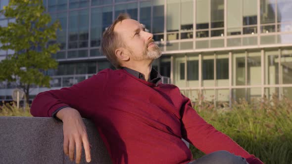 A Middleaged Handsome Caucasian Man Thinks About Something As He Sits in an Urban Area