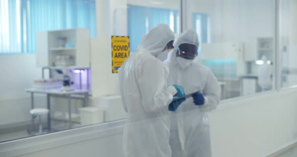 Scientists in Ppe Suit During Coronavirus Outbreak Working in Laboratory Using Tablet Pc