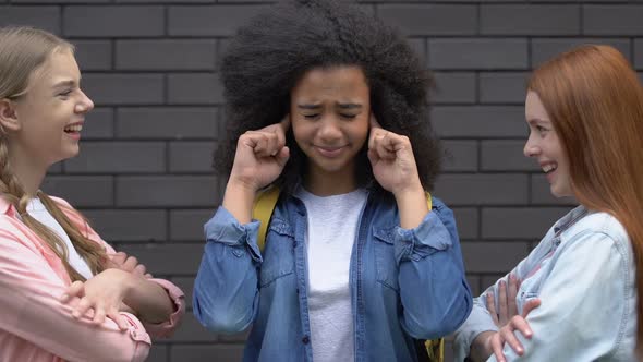 Biracial Teenage Girl Covering Ears From Bullying, Mockery of Classmates, Racism