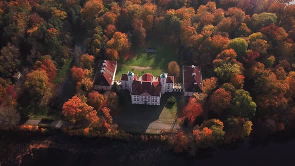 AERIAL front view of Castle. Flight over beautiful castle, located in landscape park with green tree