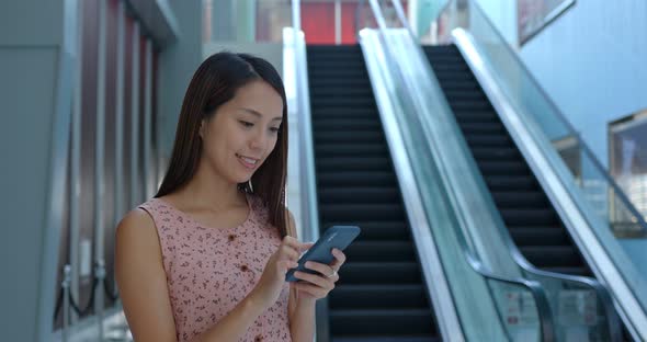 Woman use of mobile phone inside shopping mall